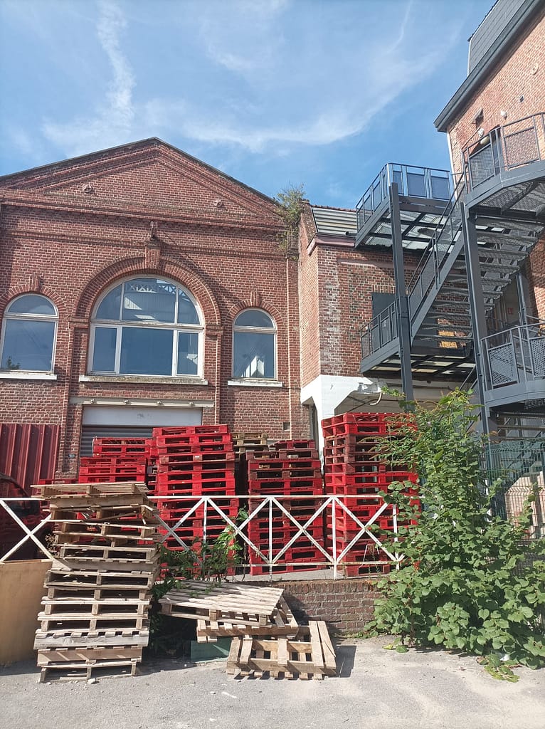 L'image montre un bâtiment en brique, avec une belle verrière: c'est la plateforme de réemploi