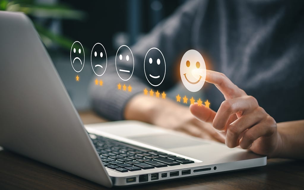 L'image montre une personne sur un ordinateur, qui clique sur un questionnaire de satisfaction (smileys souriants)