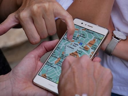 L'image montre un téléphone en gros plan avec des mains qui sont en train de montrer dessus un plan de la ville de lyon