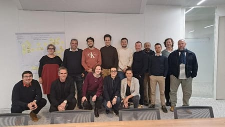 L'image montre 15 personnes posant devant un bureau. Ils sourient