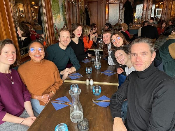 Limage montre l'équipe d'urbanova attablée au restaurant, les 8 personnes regaredent la caméra et sourient