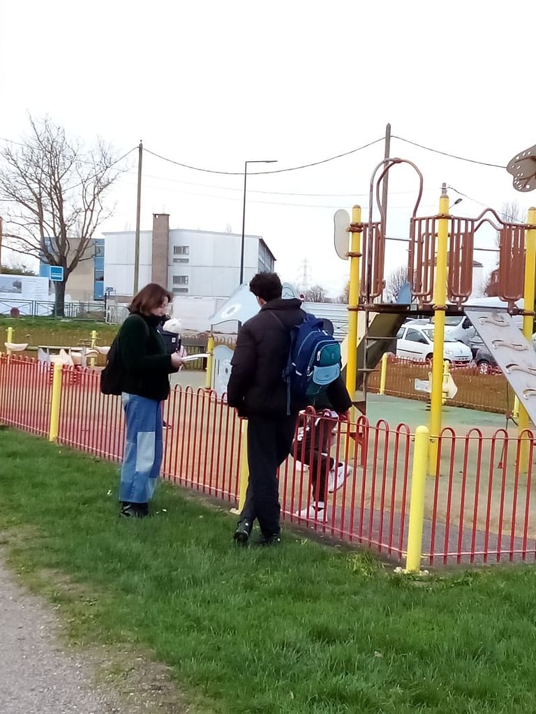 L'image montre 2 personnes en train de discuter à côté d'un parc pour enfants