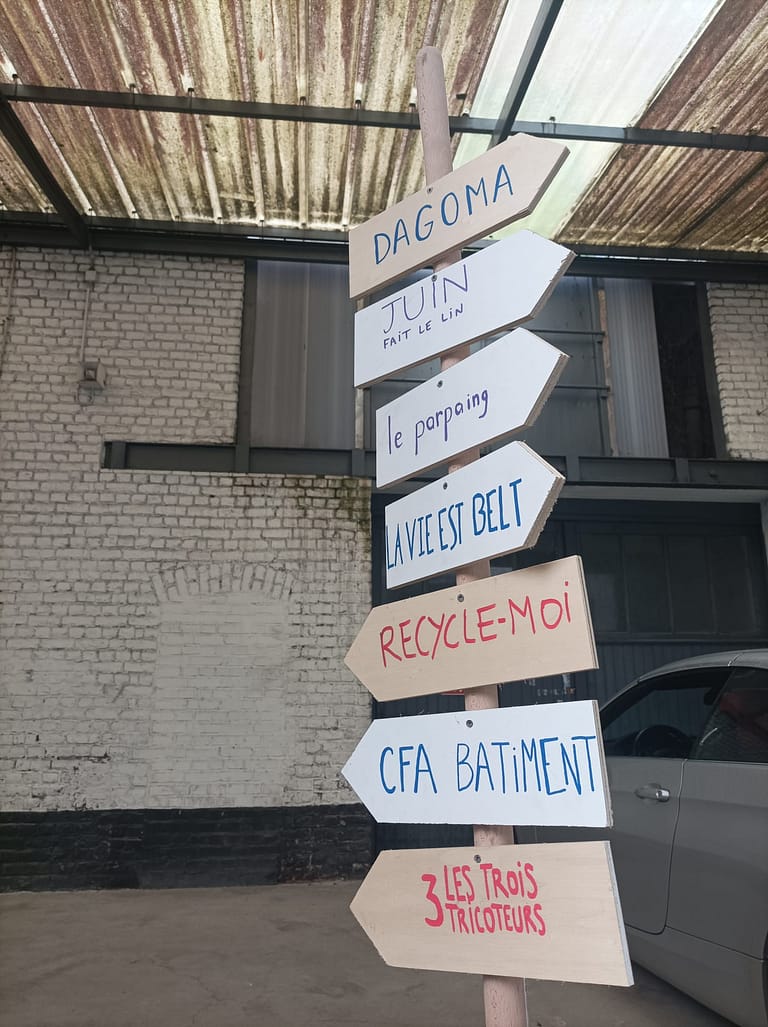 L'image montre un panneau indicateur avec les noms des différents occupants de Tissel : dagoma, la vie est belt, le parpaing, CFA BTP