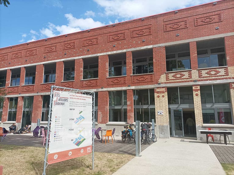 L'image montre un bâtiment en briques de 1 étage, avec devant un panneau annonçant "ateliers diderot"