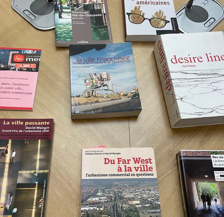 L'image montre des livres étalés sur une table : "la ville franchisée", "du far west à la ville", "la ville passante" etc.