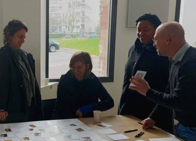 L'image montre 4 personnes autour d'une table sur laquelle est posée un plan du quartier, elles posent des cartes associées à des activités