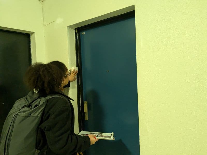 l'image montre une personne toquant à une porte dans un couloir d'immeuble