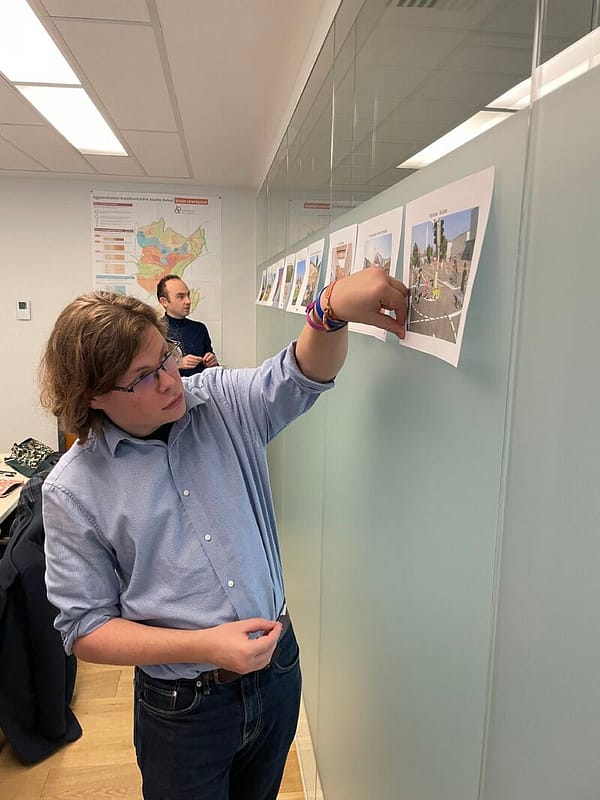 L'image montre une personne collant des gommettes sur des images imprimées collées au mur,d ans le cadre de l'atelier