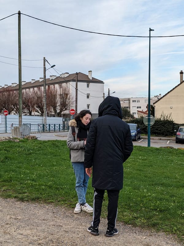 L'image montre 2 personnes debout dans un parc en train de discuter